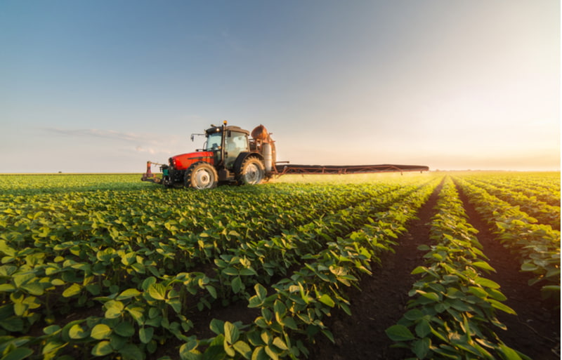 Tractor spraying pesticides on soybean