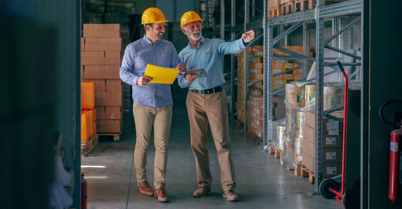 CEO going around warehouse with supervisor and talking analyzing sale statistics.