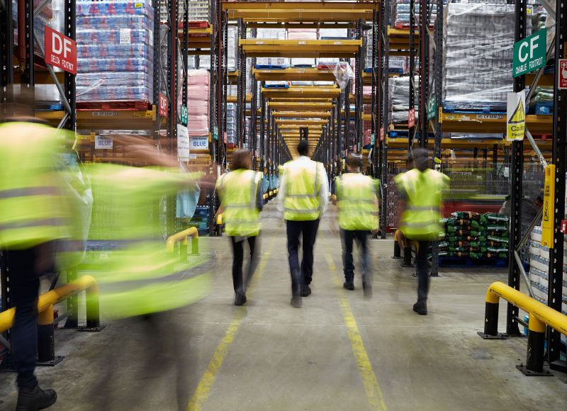 Group of Staff in reflective vests walking in a warehouse,