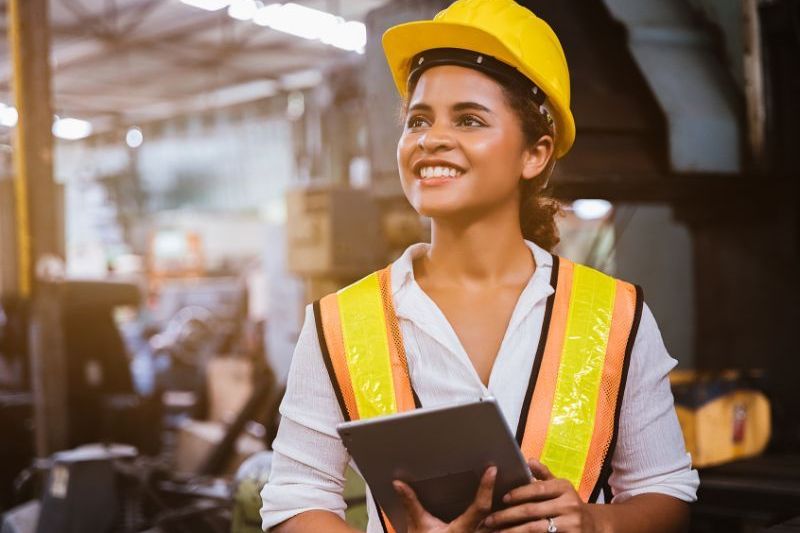 Pilot Air - Scalable air compressor solutions Industry maintenance engineer woman dark skin wearing uniform and safety helmet under inspection and checking production process on factory station by tablet.