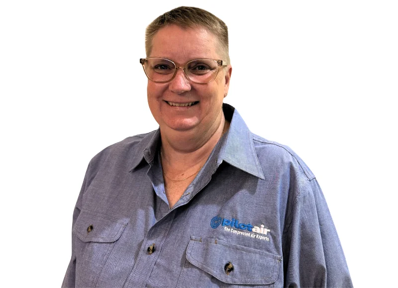Smiling woman with short hair and glasses wearing a blue work shirt with a small company logo on the chest.