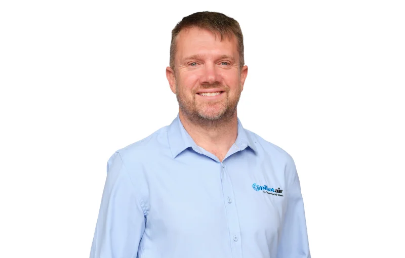 Smiling man in a light blue company shirt with Pilot Air logo on the chest.