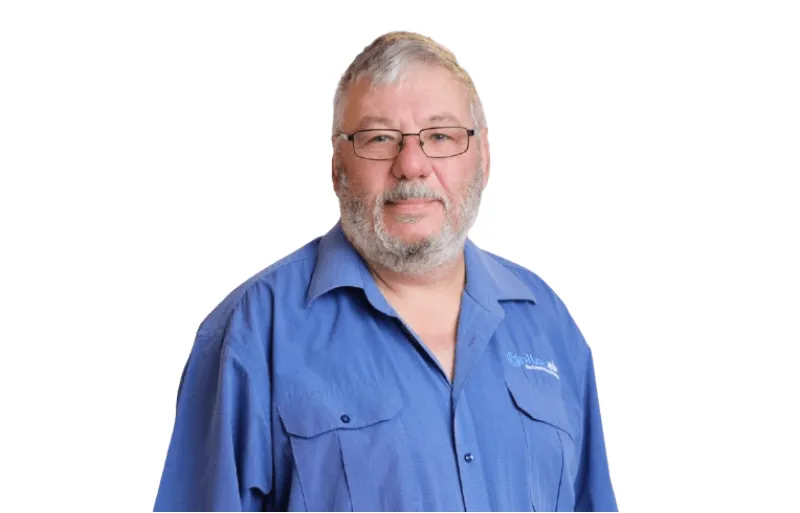 Portrait of an older man with glasses and a gray beard wearing a blue button-down shirt against a white background.