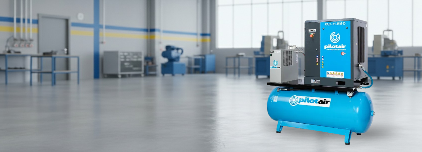Industrial workshop with a large blue Pilot Air air compressor on the right, plugged into power and ready for use